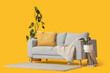 © Pixel-Shot - Cozy grey sofa with blanket, cushion and houseplants on yellow background