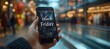 © Five Million Stock - A close-up photo of someone holding a phone with the words 'Black Friday Sale' on it, in front of a blurred-out shopping mall background,