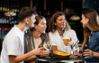 © JackF - Group of friends standing at table in bar, drinking beer and having conversation.