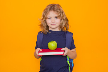 Fototapete - Child from elementary school with book and apple isolated on yellow background. Little student, clever nerd pupil ready to study. First time to school. Concept of education and learning.