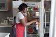 © Anna Berkut/Stocksy - woman taking food in refrigerator in kitchen, open fridge