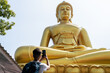 © Alvaro Lavin/Stocksy - Woman photographing big Buddha statue.