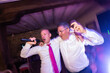 © Alvaro Lavin/Stocksy - Two cheerful businessmen singing and dancing at night party