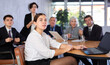 © JackF - Portrait of positive young female office worker sitting at table with colleagues, listening with interest and watching presentation during business meeting