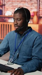 Poster - Vertical video Smiling call center agent dealing with unhappy customers, speaking with them using audio headset at office desk. Customer support worker handling clients complaints in company workspace