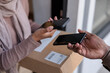 © Jovo Jovanovic/Stocksy - Woman receiving parcel and doing mobile payment