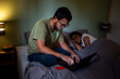 © Luis Herrera/Stocksy - Man using laptop with credit card while partner sleeps