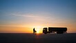 © Ratchadaporn - Silhouette of a fuel truck and a worker standing next to it on a backdrop against a colorful sunrise sky