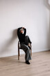 © Viktor Solomin/Stocksy - Woman sitting on a chair in a minimalist room during daytime