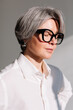 © Viktor Solomin/Stocksy - Stylish older woman with short grey hair enjoys the sunlight