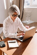 © Viktor Solomin/Stocksy - Woman working diligently on a laptop in a bright modern office