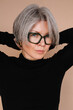 © Viktor Solomin/Stocksy - Woman with gray hair and glasses poses confidently