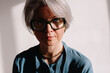 © Viktor Solomin/Stocksy - Distinctive portrait of a woman with silver hair and large glasses
