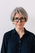 © Viktor Solomin/Stocksy - Woman with stylish glasses and short gray hair