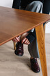 © Viktor Solomin/Stocksy - Individual tying shoelaces while seated at a wooden table