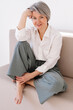 © Viktor Solomin/Stocksy - Middle-aged woman sitting comfortably on a sofa