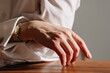 © Viktor Solomin/Stocksy - Elegant hand resting on a wooden table with soft light
