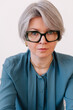 © Viktor Solomin/Stocksy - Professional woman with short gray hair and glasses closeup
