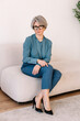 © Viktor Solomin/Stocksy - Woman in stylish outfit seated on modern couch in a bright room
