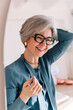 © Viktor Solomin/Stocksy - Joyful older woman smiling while touching her hair