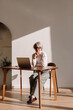 © Viktor Solomin/Stocksy - Elderly woman working thoughtfully at a desk in a sunlit room