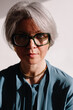 © Viktor Solomin/Stocksy - Woman with silver hair and green glasses poses thoughtfully