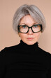 © Viktor Solomin/Stocksy - Mature woman with short gray hair and oversized glasses