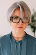 © Viktor Solomin/Stocksy - Elegant woman with silver hair and glasses