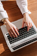 © Viktor Solomin/Stocksy - Working on a laptop at a wooden desk during the day