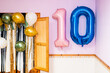© Alvaro Lavin/Stocksy - Pink and blue number ten balloons hanging on wall