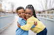 © Santi Nuñez/Stocksy - Two happy children hugging on a bridge in a park