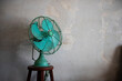© Lawren Lu/Stocksy - Vintage Teal Fan on Wooden Stool against Rustic Wall