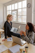 © BONNINSTUDIO/Stocksy - Formal businesswomen discussing work in modern office with laptops