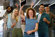 © NDABCREATIVITY - Happy young successful business team celebrating a triumph with arms up in startup office.
