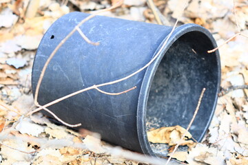 Poster - A black trash can sits atop a pile of autumn leaves.