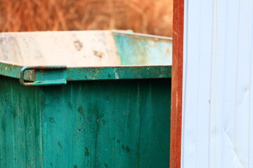 Poster - A close-up shot of a small green trash can with a lid and handles.