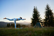 © anatoliy_gleb - Woman practicing yoga outdoors in the mountains in a serene, natural setting near tourist tent. Female performing yoga pose on mat, with backdrop of beautiful mountain landscape at sunrise or sunset.