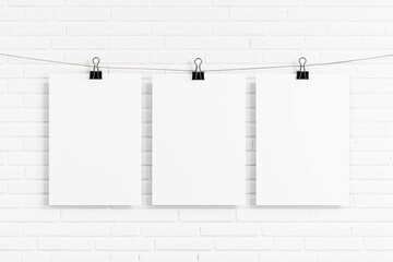 Aufkleber - Blank white posters hanging with binder clips on a string against white brick wall.