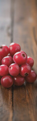 Poster - A pile of vibrant red berries, possibly cranberries, are arranged on a rustic wooden surface, showcasing their smooth texture and natural appeal.