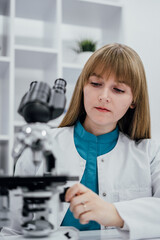 Aufkleber - A scientist in  white lab coat and blue uniform is carefully adjusting microscope to observe samples in detail. The modern laboratory setting with clean shelves  tools creates professional atmosphere