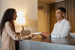 © Meeko Media - Receptionist Assisting a Traveler in a Modern Hotel Lobby