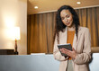 © Meeko Media - Professional Woman Using a Tablet at a Hotel Reception Desk in Business Environment