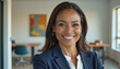 © f_bossa - A portrait headshot photo of a friendly professional CEO executive business worker: A smiling African American businesswoman in a navy blazer and white blouse confidently looks at the camera in a