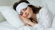 © rdkcho - Serene Young Woman Sleeping Peacefully in Bed Wearing a Striped Sleep Mask