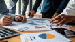 © maju - Business team collaborating on charts and graphs at a meeting.  Close-up view of hands working on financial documents.