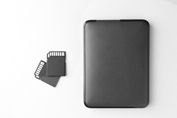 Poster - External hard drive and SD memory cards on white background, flat lay