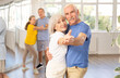 © JackF - Smiling senior woman and man dancing slow ballroom dance during group class in choreography studio