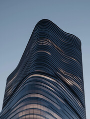 Poster - modern skyscraper with wavy facade stands against clear sky, showcasing sleek architectural design