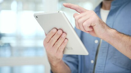 Close up of male hands holding digital tablet at workplace in modern business office. Adult businessmen using working on application, typing message, chatting, banking or swiping browsing online