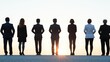 © Preecha - a line of businesspeople standing tall in silhouette with sunrise lighting up the horizon evoking themes of trust and leadership ideal for a professional poster with ample area for promotional text